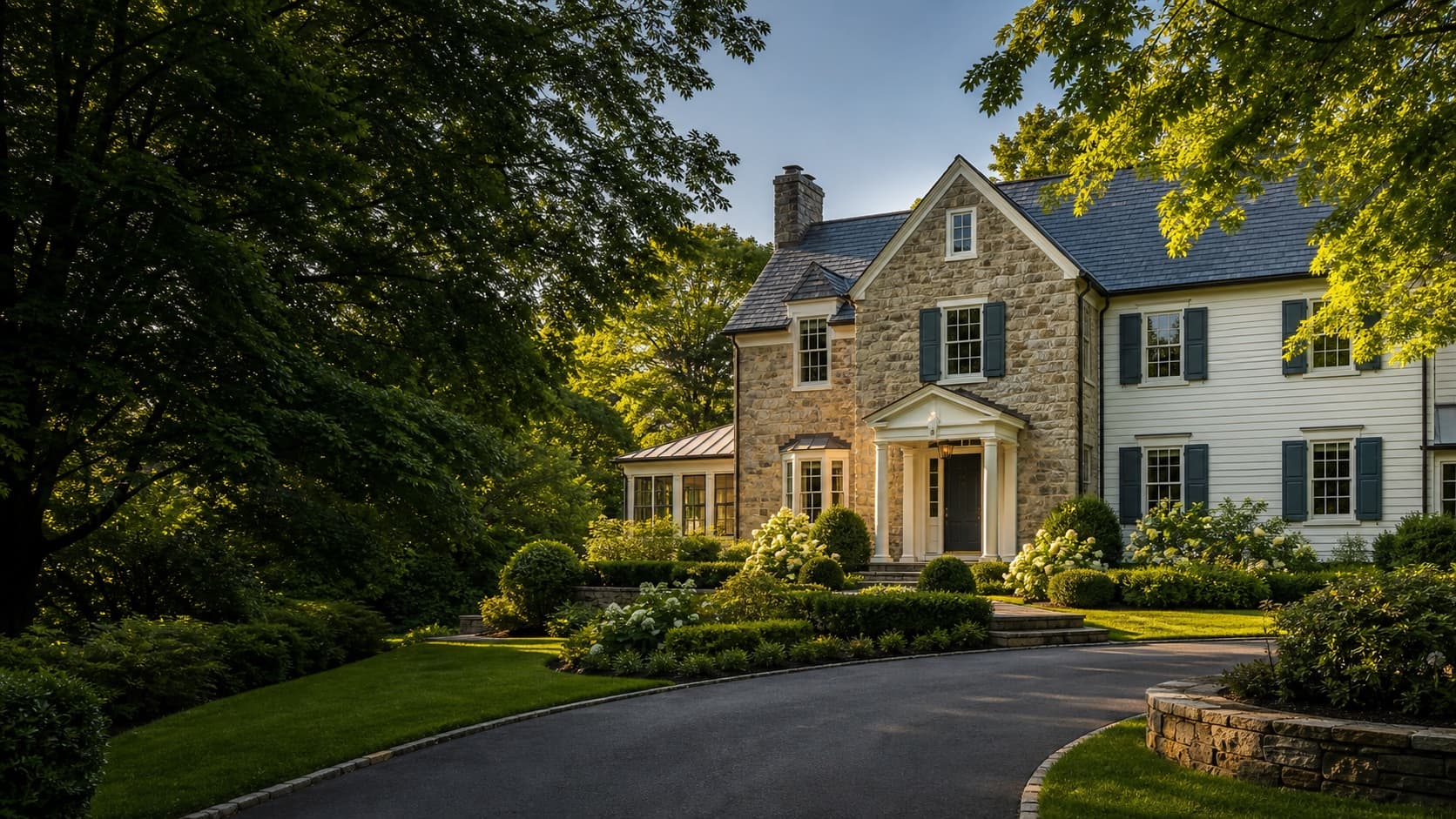 Elegant stone home surrounded by mature green trees in summer